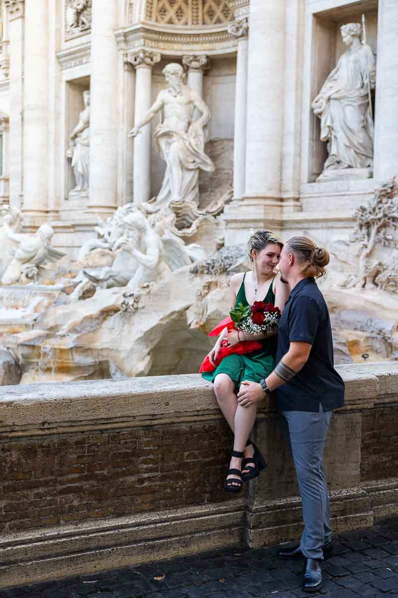 Full figure framed couple while engaged after getting engaged at the main fountain where he asked and proposed to her by the water