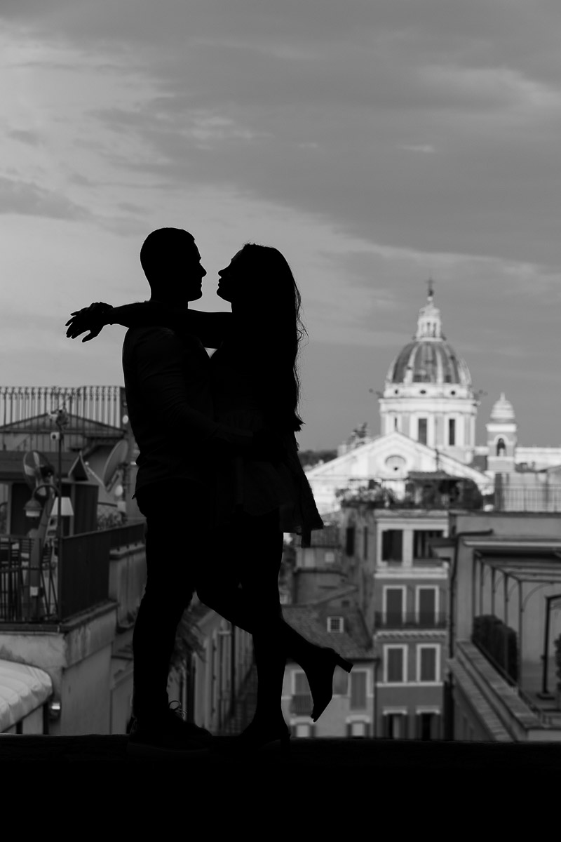 Black and white silhouette image of a couple posing in front of cityscape