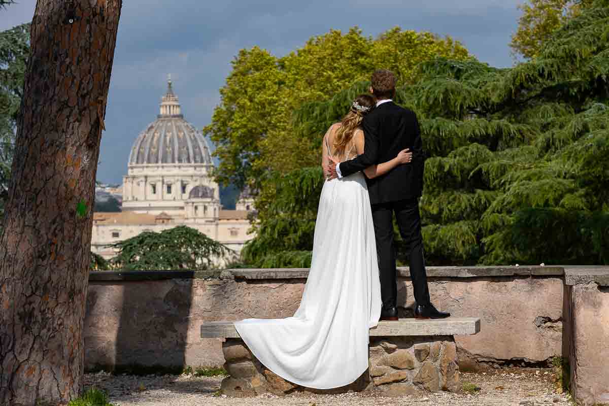 Wedding photoshoot with the bride and groom admiring the view of the Saint Peter's cathedral dome in the far distance. Rome Wedding Photography and Videography service