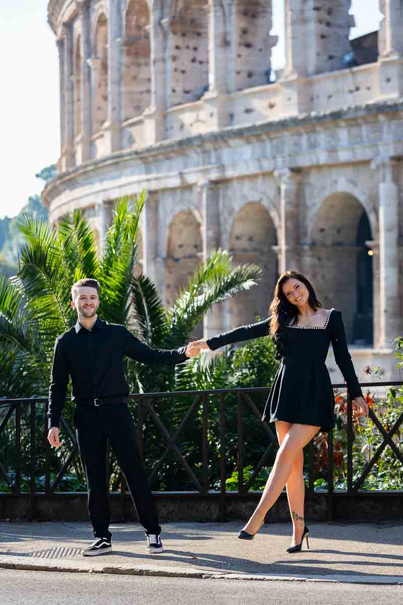 Couple holding hands while taking photos by the Colosseum for their engagement pictures