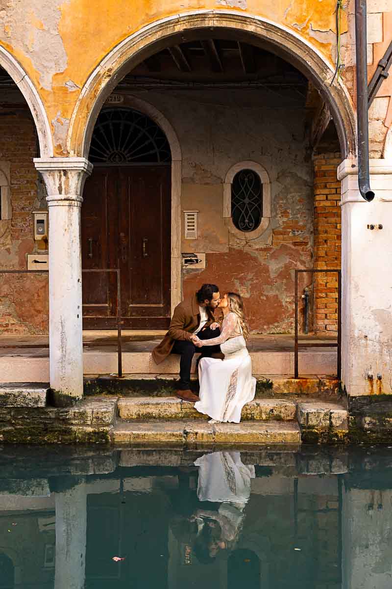 Couple taking pictures in Venice Italy after a surprise wedding proposal. Now non a photoshoot among scenic porticos and water canals 