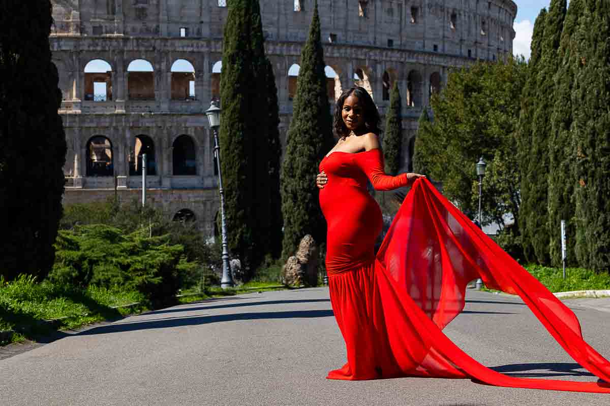 Solo maternity flying dress photos red front Colosseum Roman capital of Italy. Picture taken park overlooking the monument from a side street