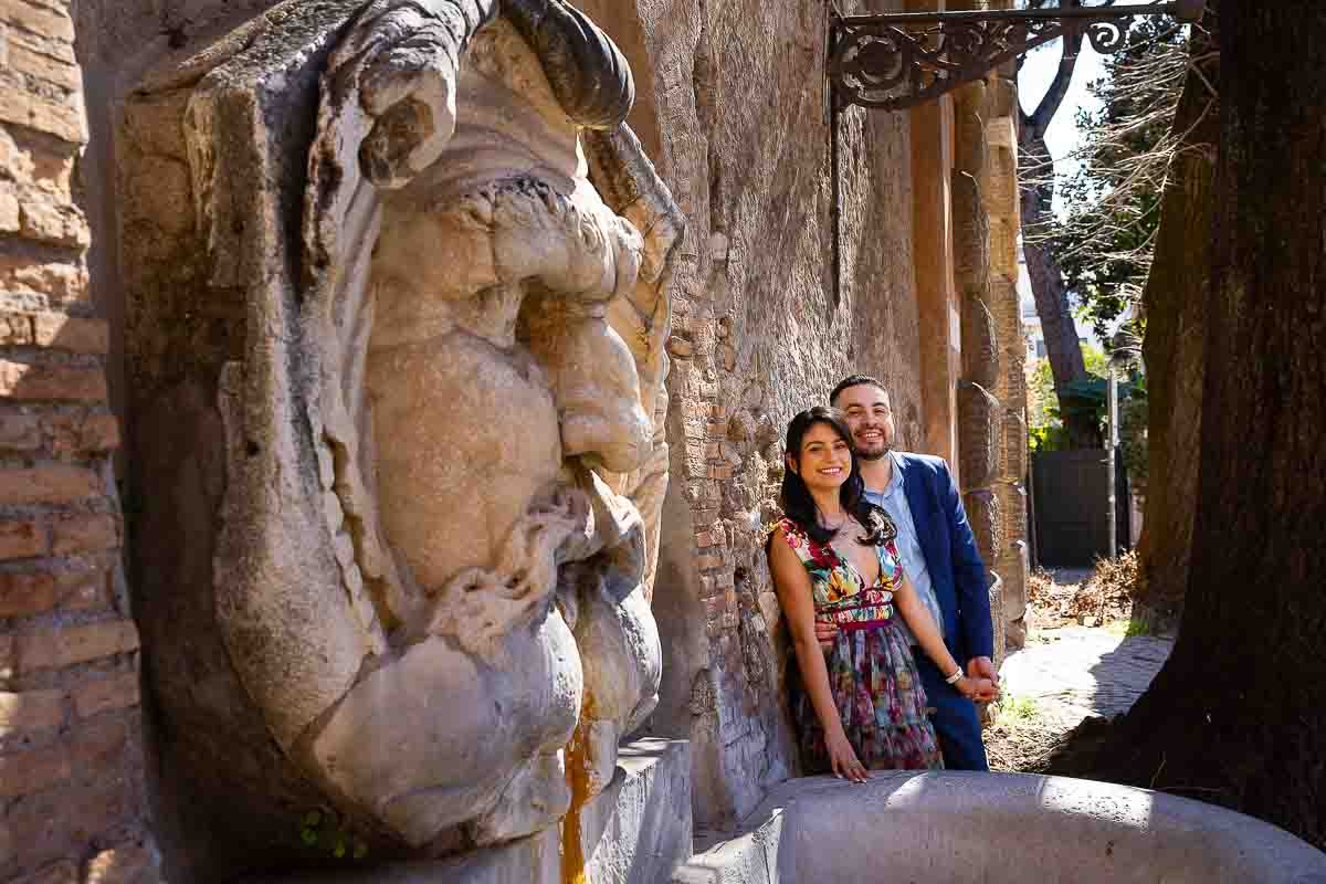 Portrait picture depicting a couple photographed by an ancient roman statue entrance of Giardino degli aranci