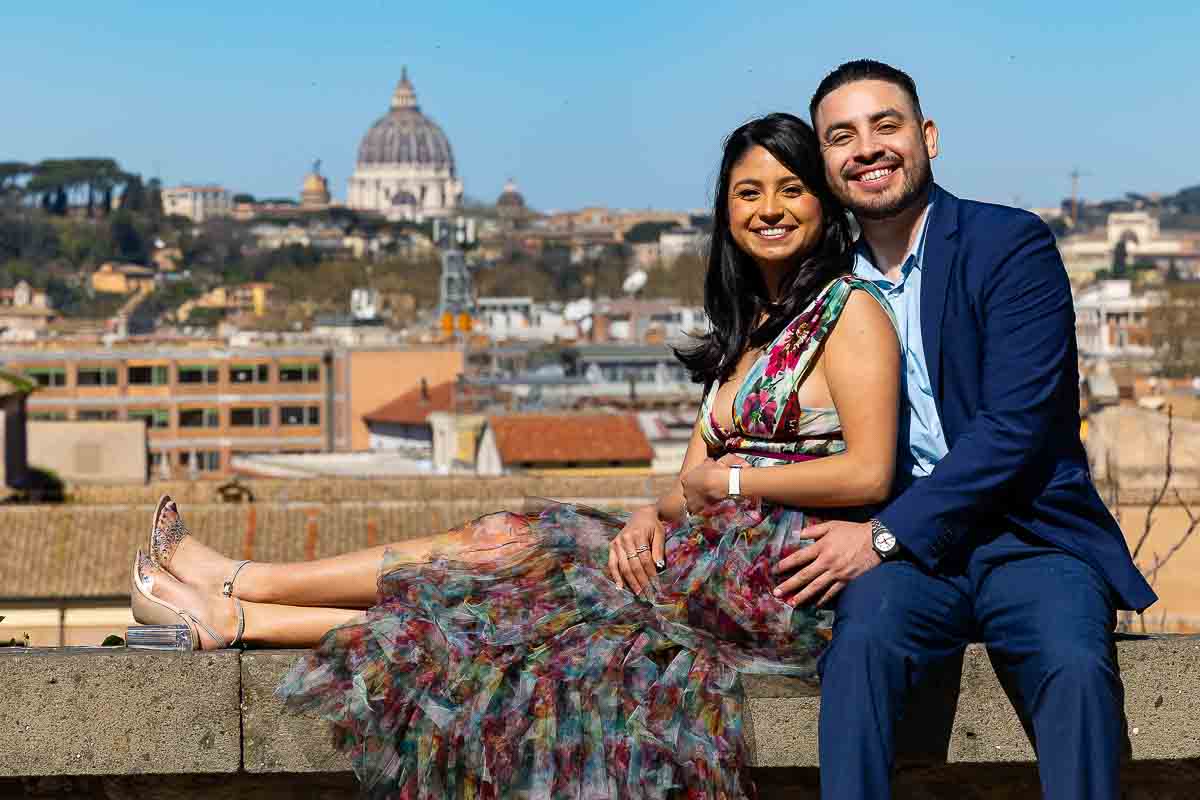 Cityscape couple photos sitting down by the roman skyline smiling.
