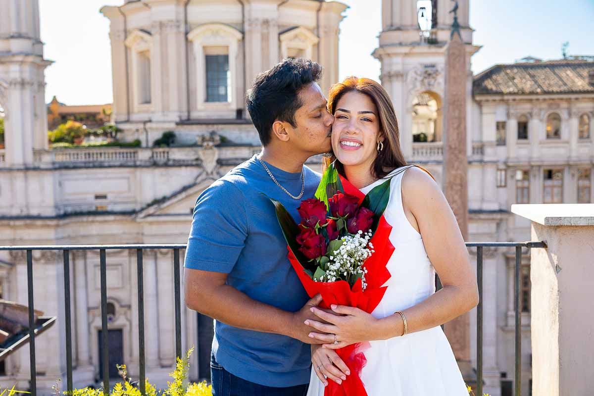 Kissing with a bouquet of red roses after a Rome rooftop proposal