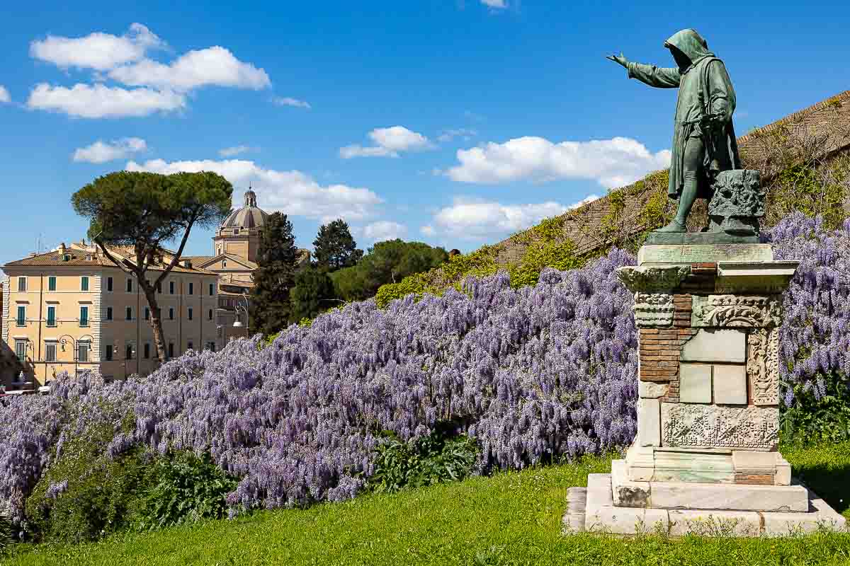 Landscape photography of the Giordano Bruno statue, surrounded by vibrant purple flowers, during a photography session in Italy