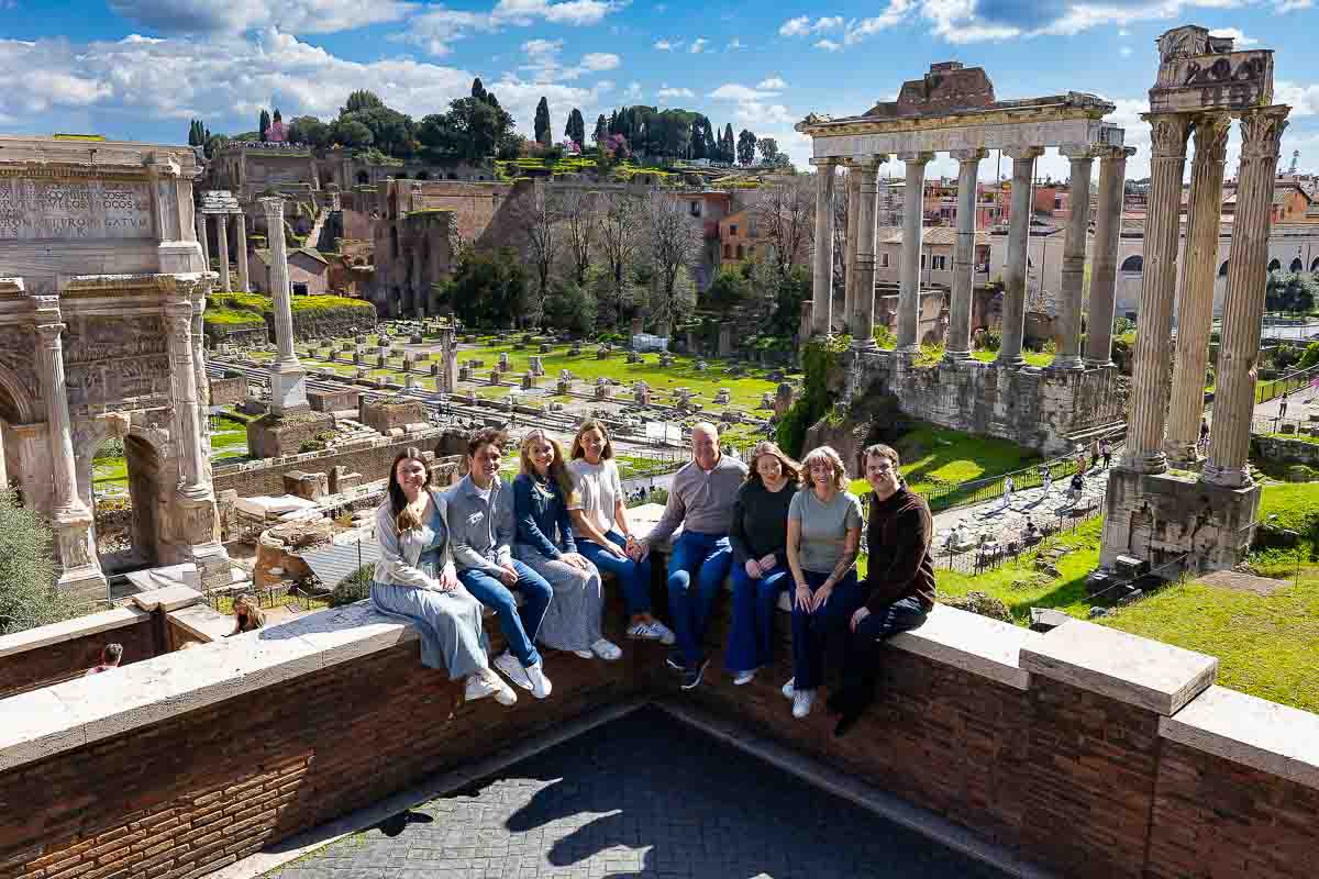 Wide-angle view of a family posed portrait at the Roman Forum, captured during a photoshoot in Rome, showcasing the ancient ruins and historic landmark