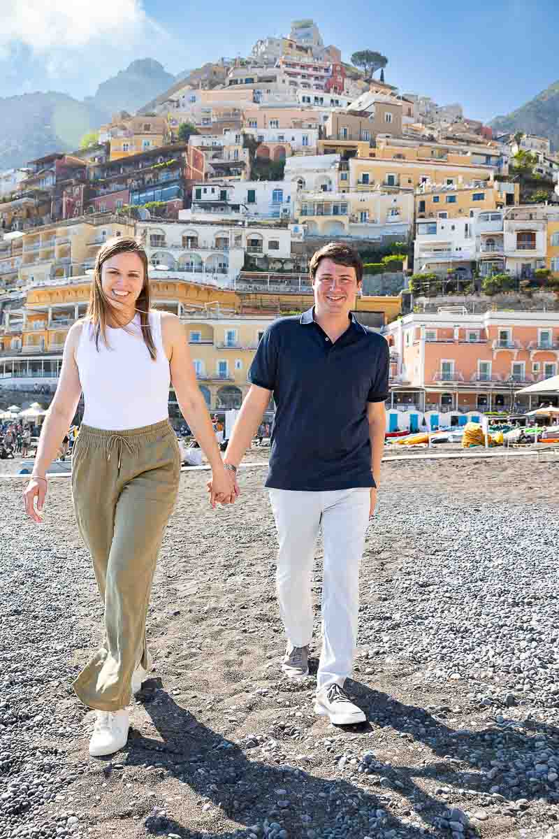 Walking hand in hand on the beach with the vertical town as a photographic background 