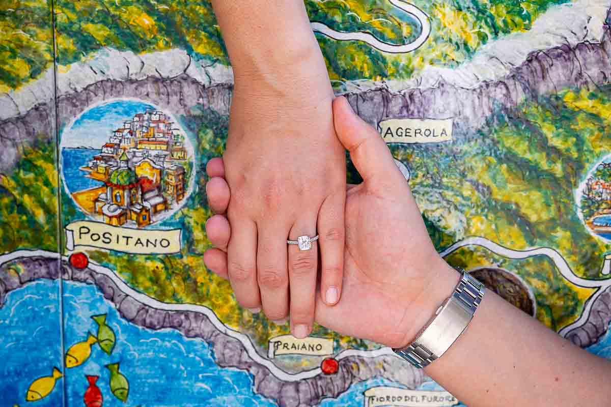 Holding hands showing off the engagement ring revealing the map Amalfi coast on a ceramic surface 
