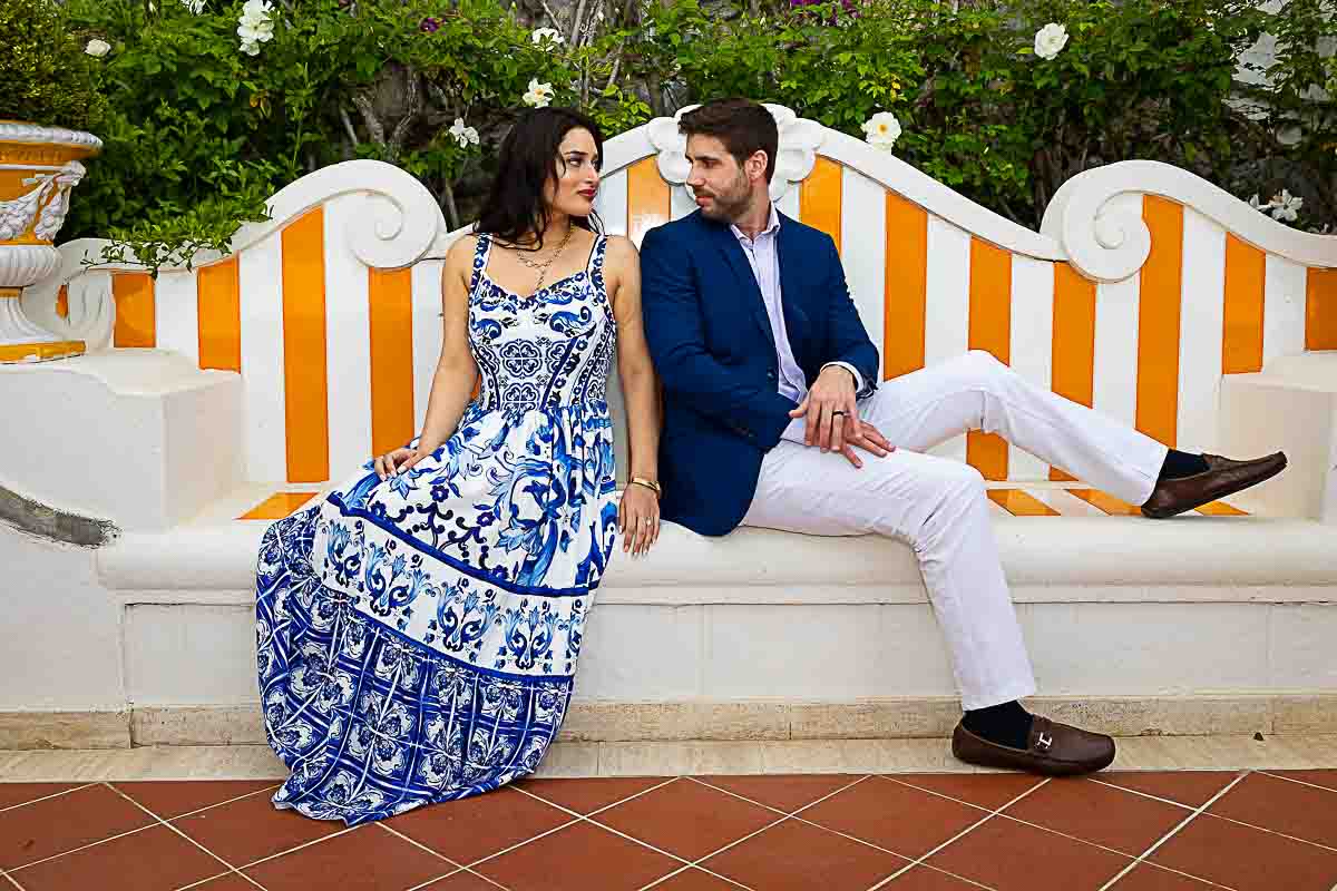 Sitting down looking at each other while taking pictures on an orange and white ceramic bench