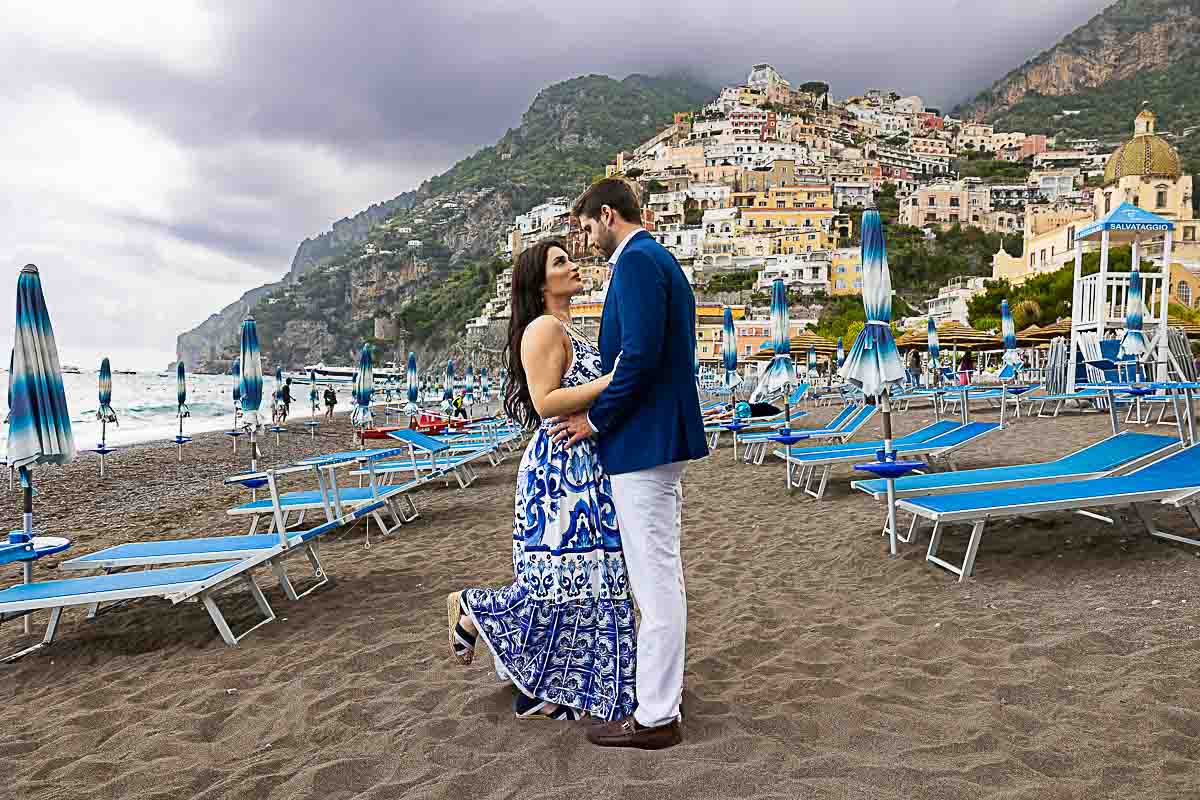 Picture taking on the beach with the small village behind the couple posing for a photo shoot