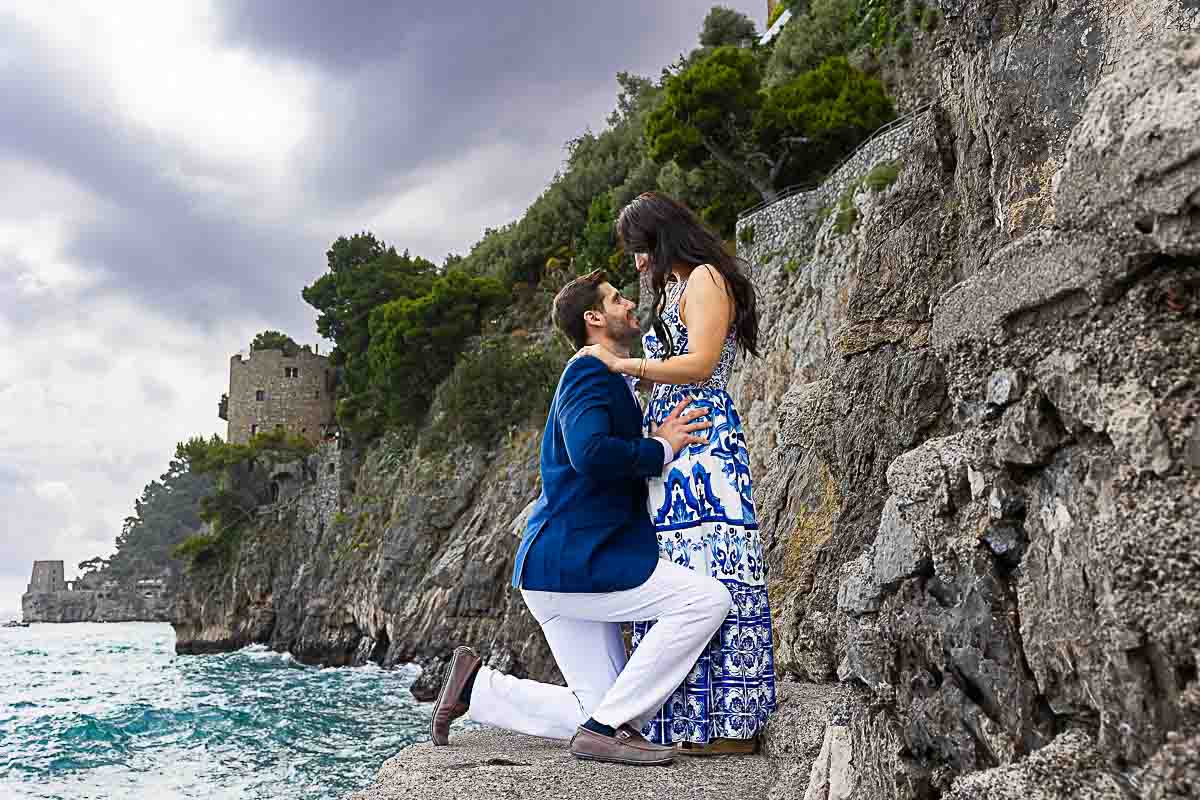 Knee down engaged picture on the rocks and over the sea Positano Couples Photoshoot