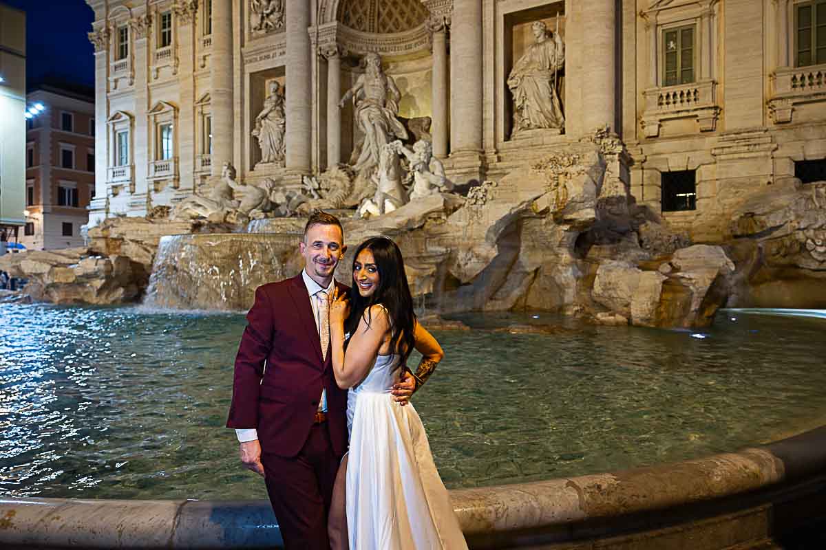 Picture taking Trevi fountain with a wedding couple posed to take pictures during a nighttime photo shoot