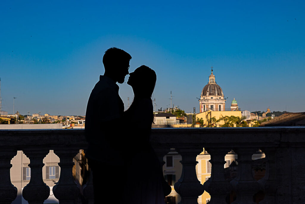 Silhouetted couple looking over Rome from Parco del Pincio terrace at sunrise.