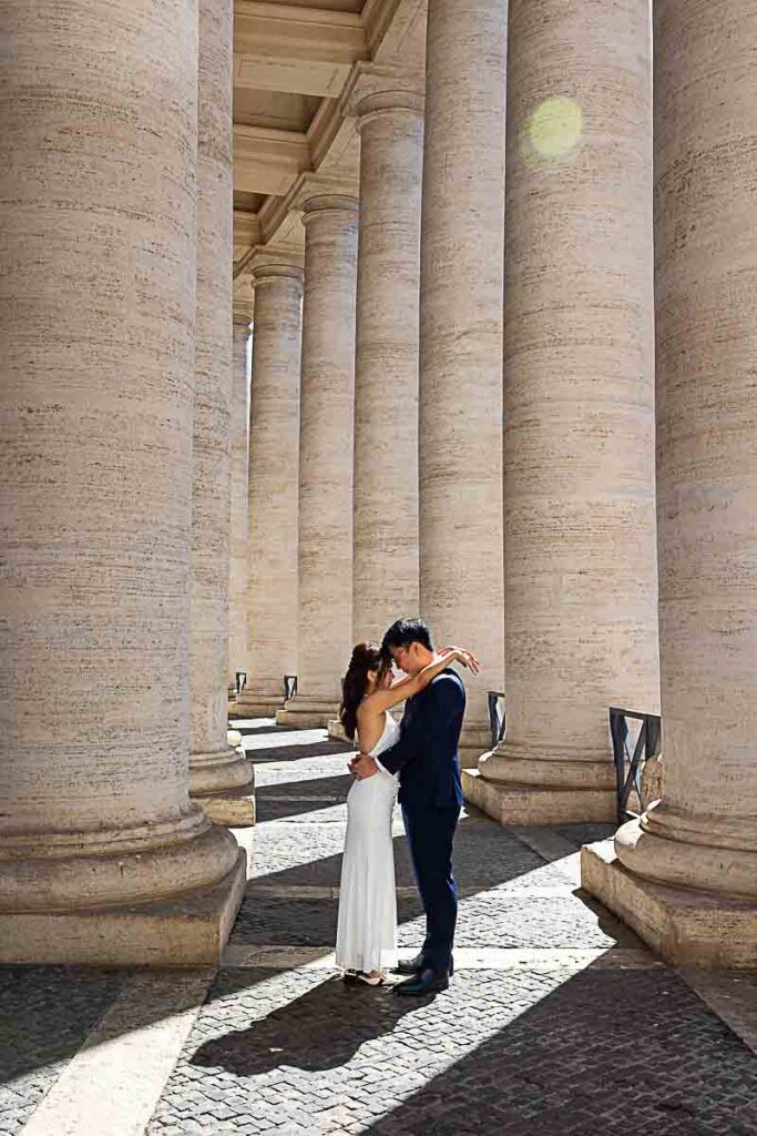 Rome wedding photo session color images taken underneath the vatican columns with light shining through the sides