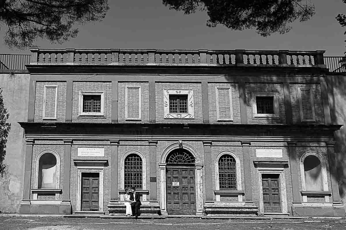 B&W image of a couple photography while sitting down on an ancient roman building