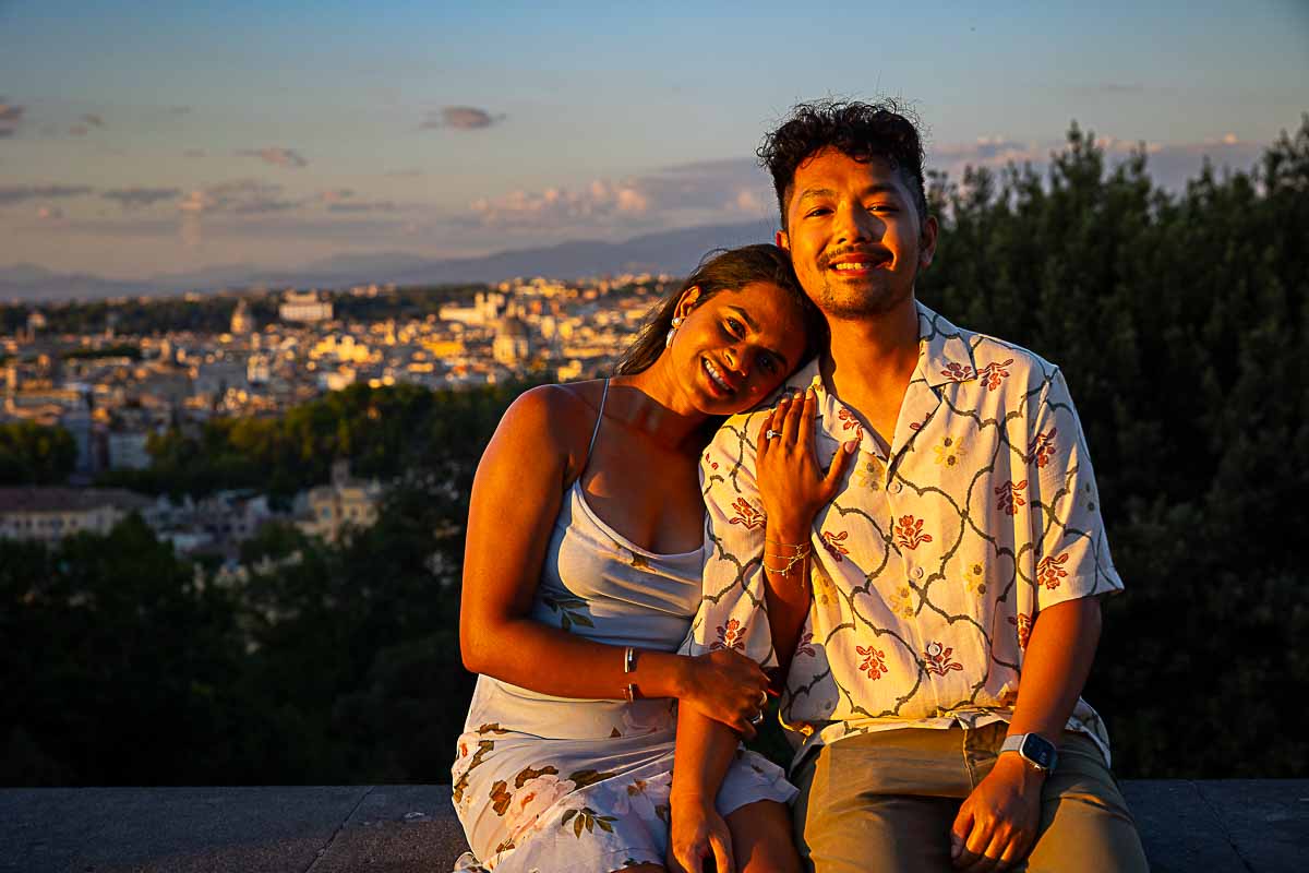 Sitting next to one another while taking picture together with the soft sun setting light shining on them during photos