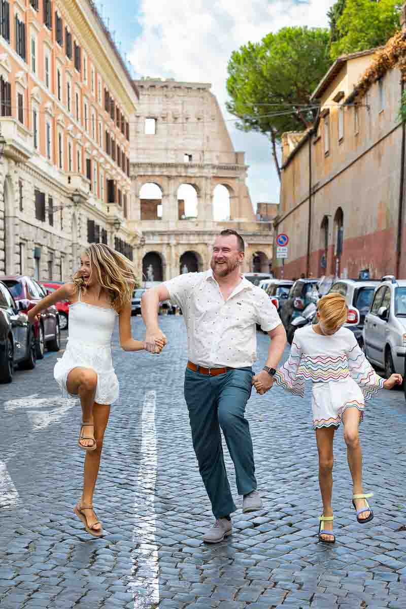 Funny walk on a cobblestone alleyway with the Colosseum in the background. having fun during the photoshoot photography session. Rome family walk photoshoot