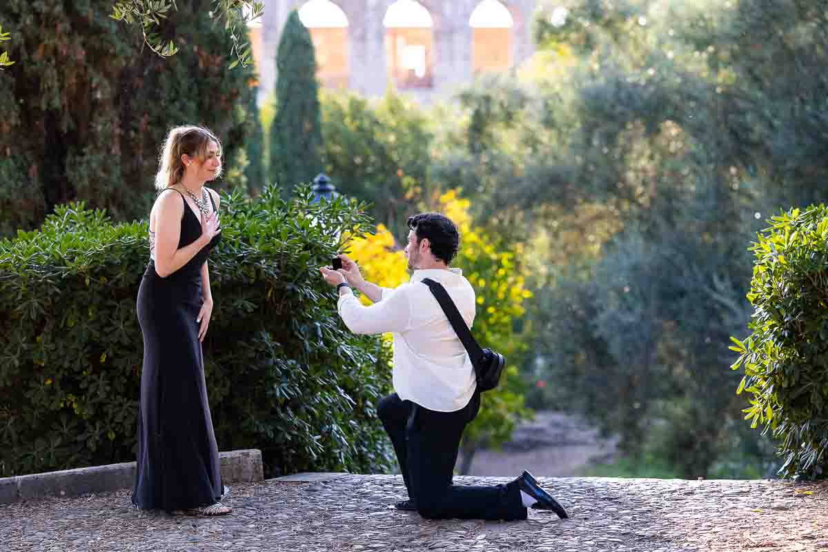 Kneeling down for a surprise proposal candidly photographed Roman Colosseum at sunset in Rome in both photo and video