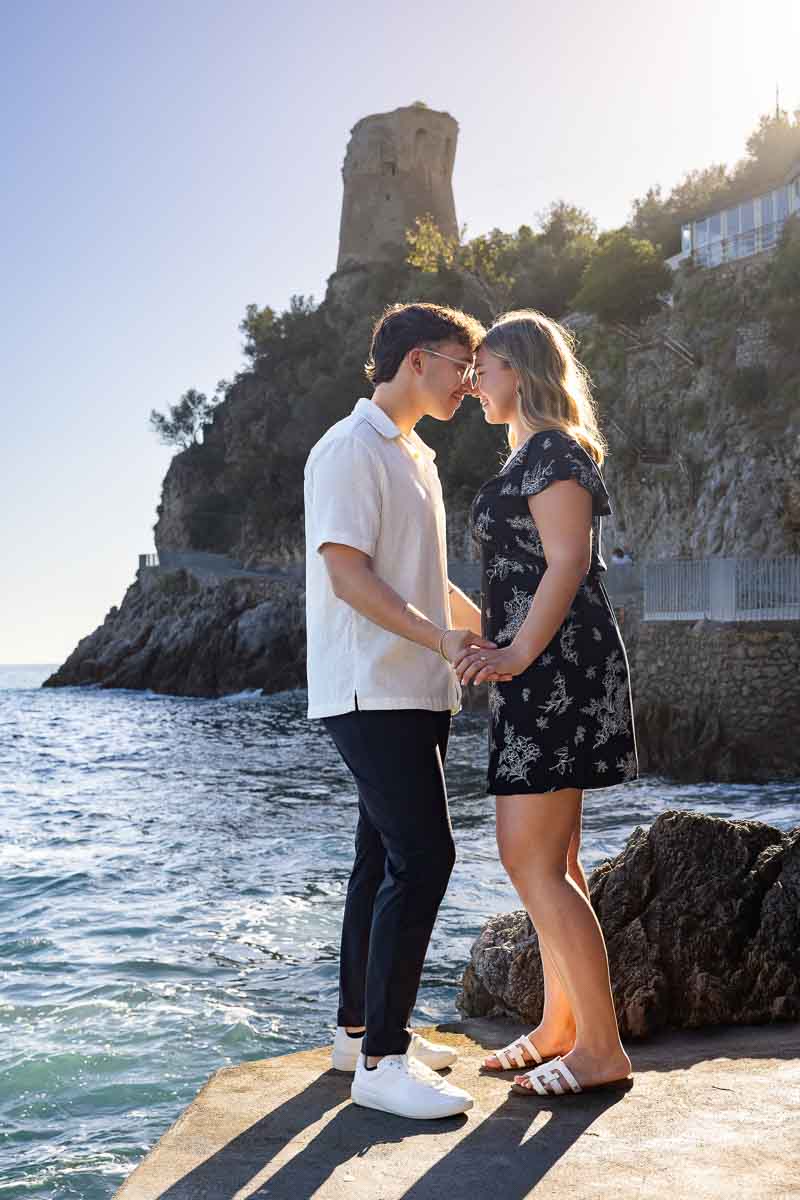 Standing together by the sea during an engagement pgotoshoot next to the water with the saracen tower in the back