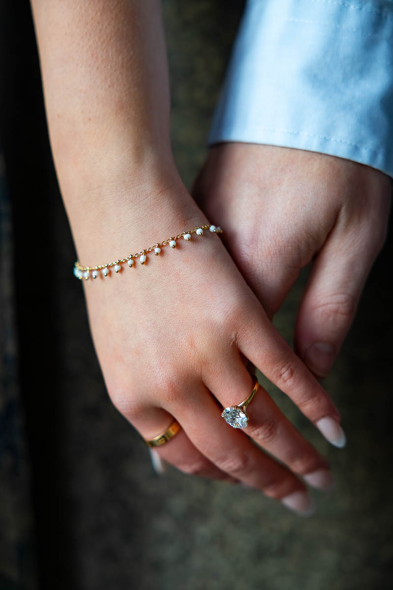 Picture of touching hands with engagement ring worn with a bracelet and diamond