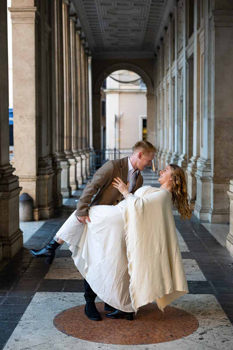Romantic standing beneath the portico in Piazza di Montecitorio with architectural lines and natural daylight framing the scene performing the dip pose for the camera