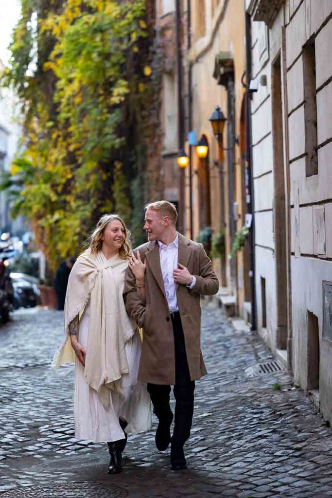 Walking on cobblestone alleyway streets holding on to each other while on a photoshoot in Rome Italy
