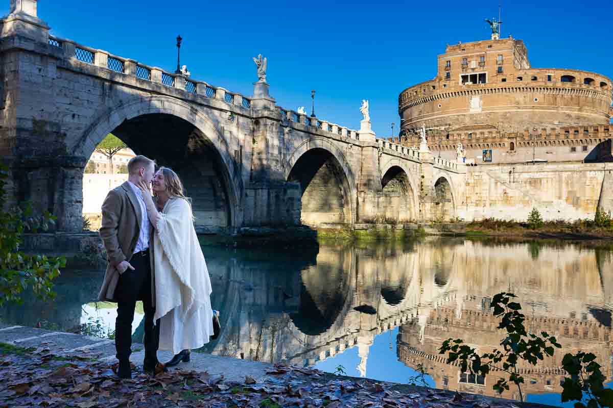 Posed next to the bridge by the Tiber river taking just engaged photos during holiday