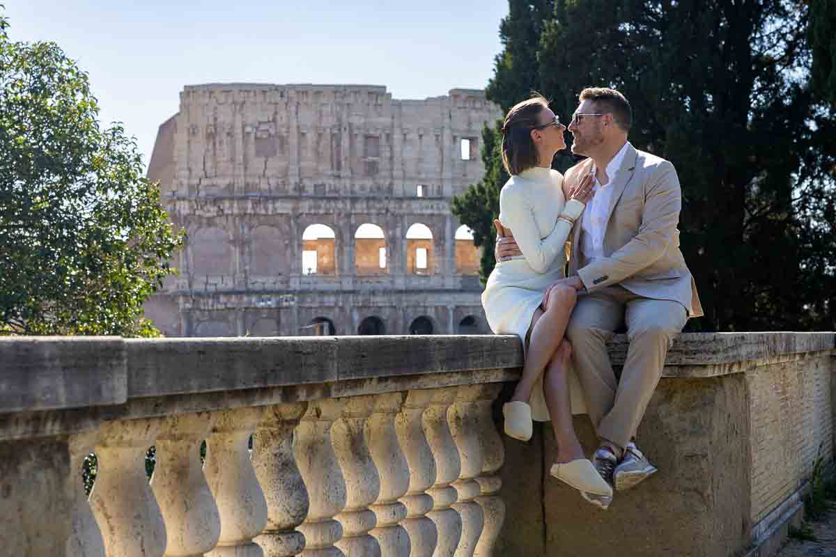 Sitting down kiss photo in front of the Coliseum after the surprise engagement