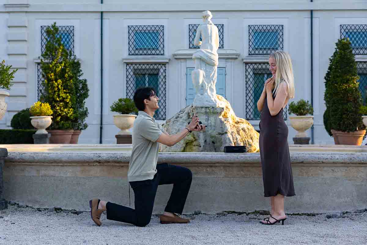 the proposing moment in which he kneels down to ask her for her hand at the garden museum right by the water fountain