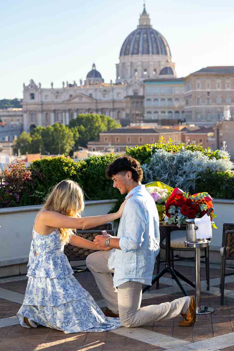 kneeling down together by the surprise of the marriage proposition during a photoshoot documenting the event from a distance