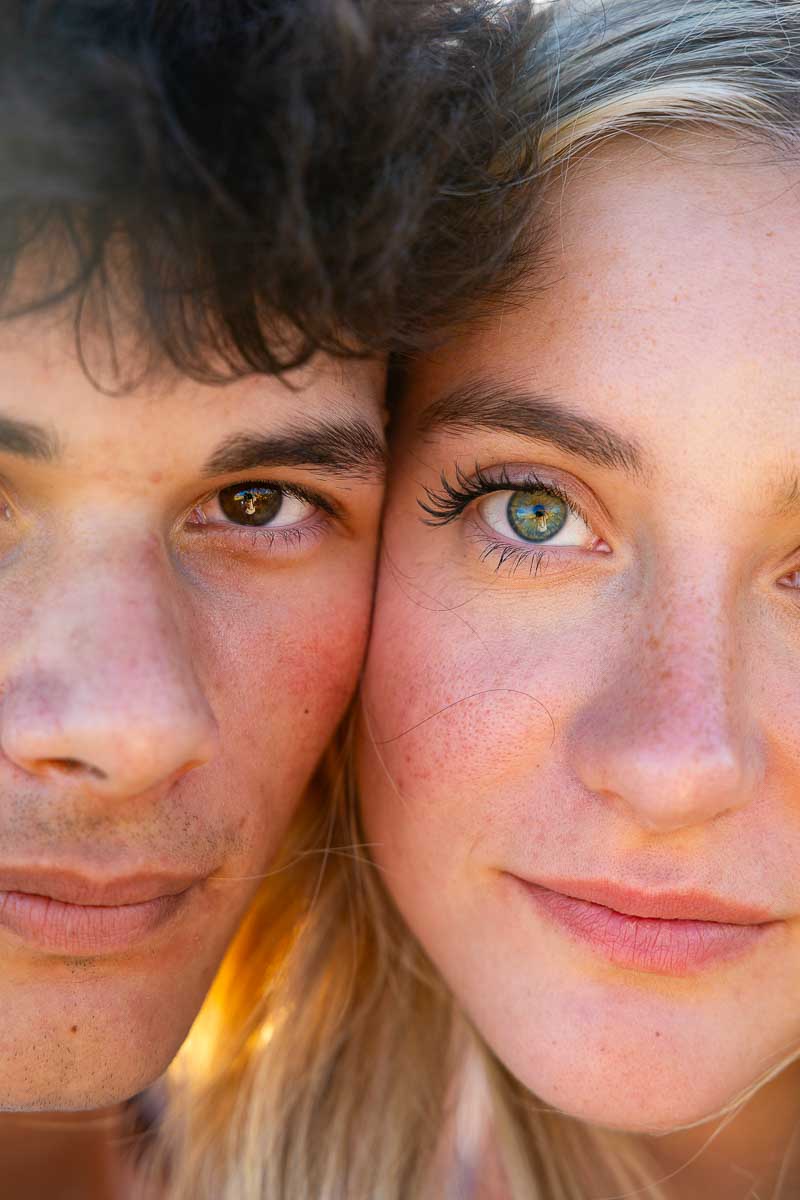 Closeup image of a couple looking back into the camera using a 50 mm portrait lens taking photos at sunset shooting against the sun