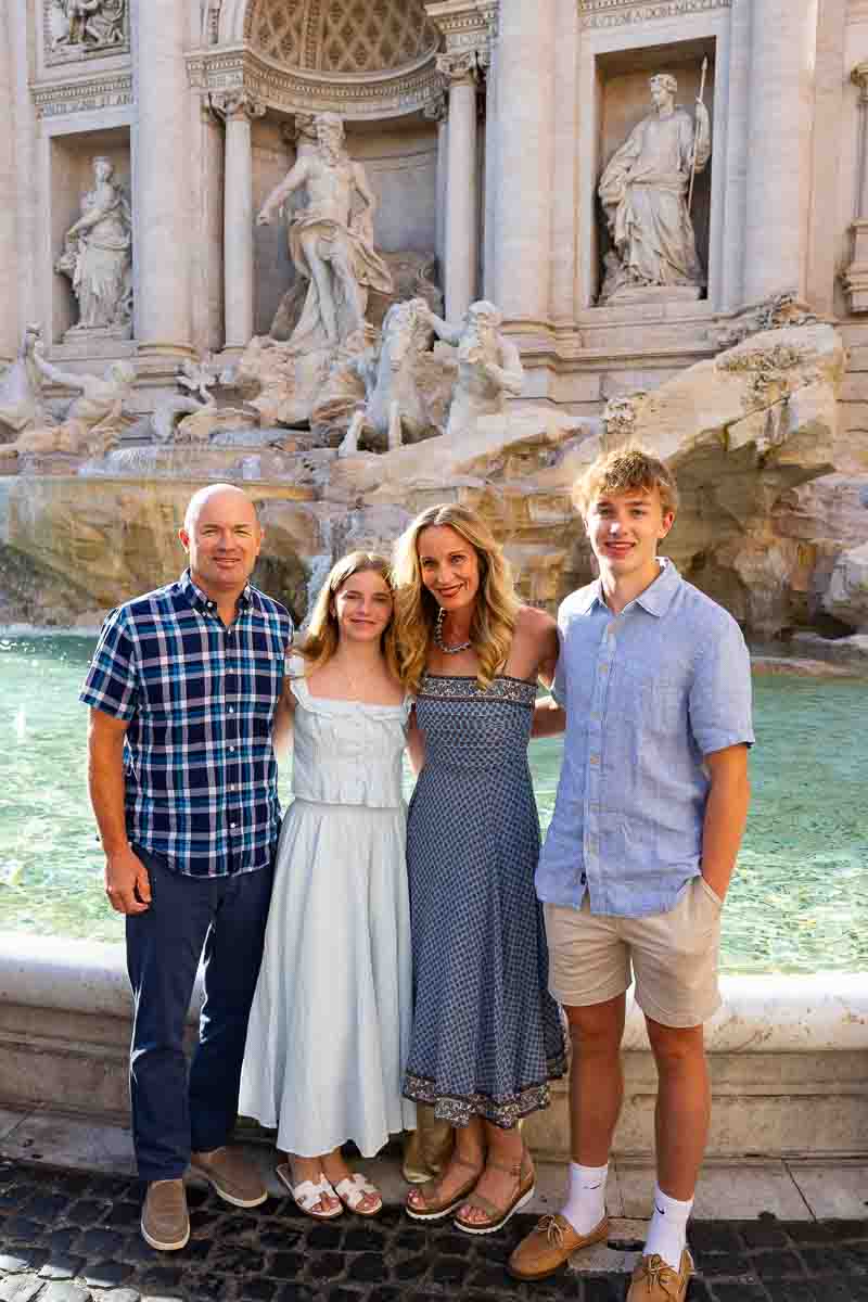 Family standing in front of Trevi fountain taking pictures together standing next to one another