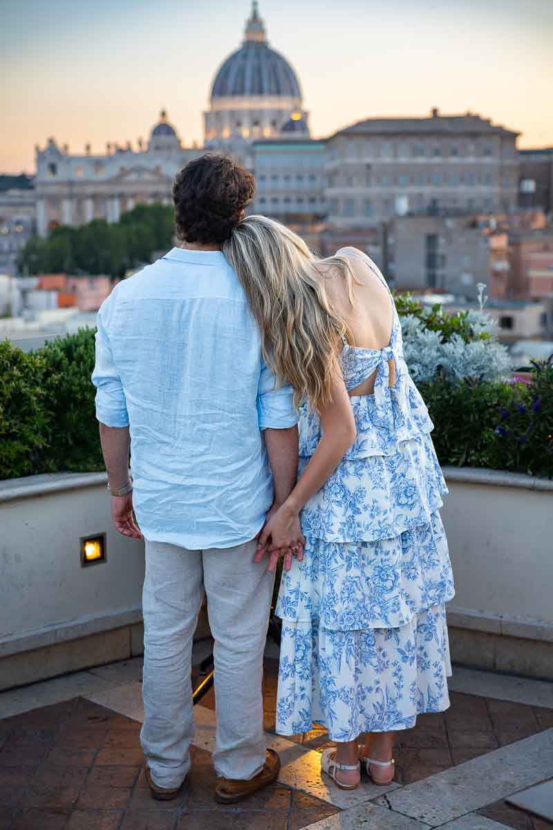 Leaning on one another and looking at the Vatican cathedral dome as the sun started to sink below the horizon. Elegant and romantic photo session with professional photography