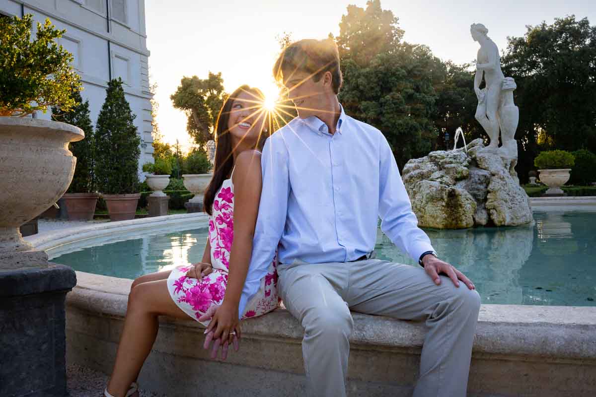 Sitting on the edge of a fountain and taking photos together during a lifestyle photo session with a professional photographer from Rome
