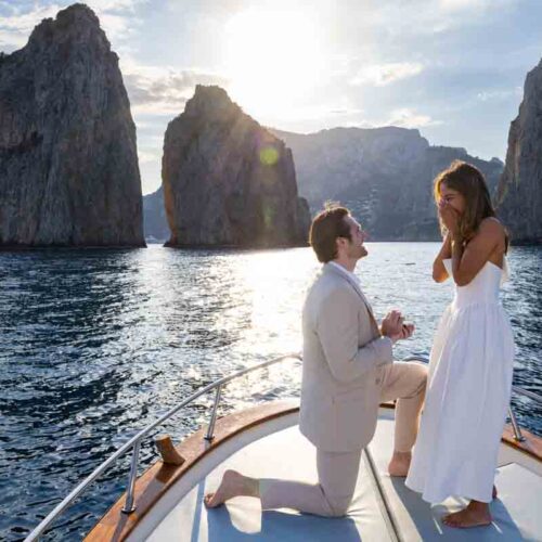 Knee down boat proposal in Capri photographer professionally by Andrea Matone photographer stranding on the vessel with the faraglioni rocks as perfect backdrop