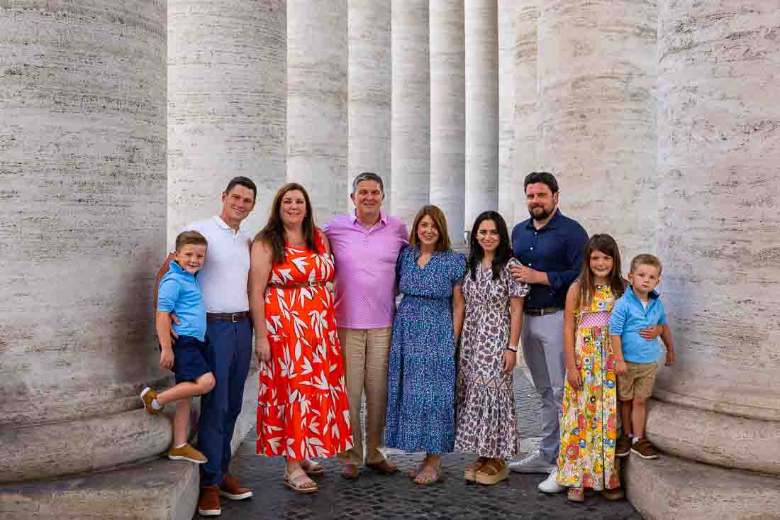 Group portrait of people beneath the colonnade of Saint Peter’s Square in Vatican City during a photography session in soft shaded light