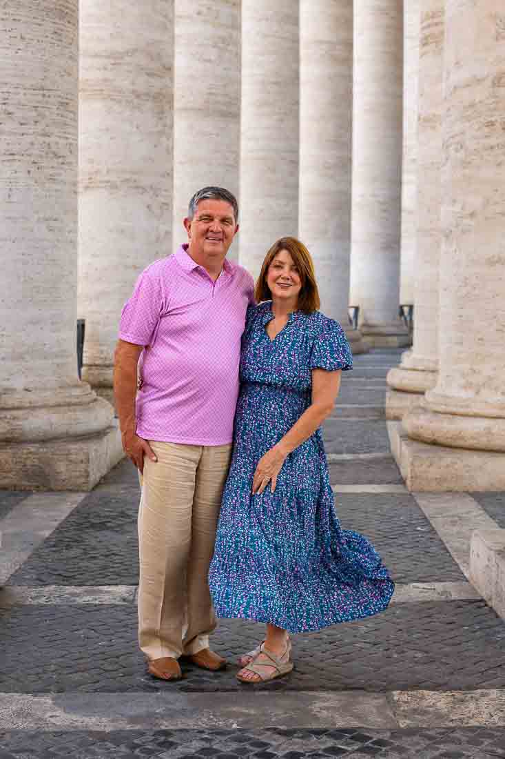 Portrait of grandparents standing together beneath the colonnade of Saint Peter’s Square in Vatican City during a guided portrait shoot in gentle natural shadow conditions