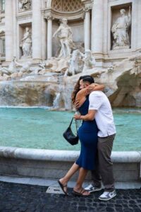 003-kiss-celebration Couple sharing a warm embrace after the engagement moment, captured in a natural portrait with the fountain surroundings creating a vibrant backdrop for this heartfelt memory.