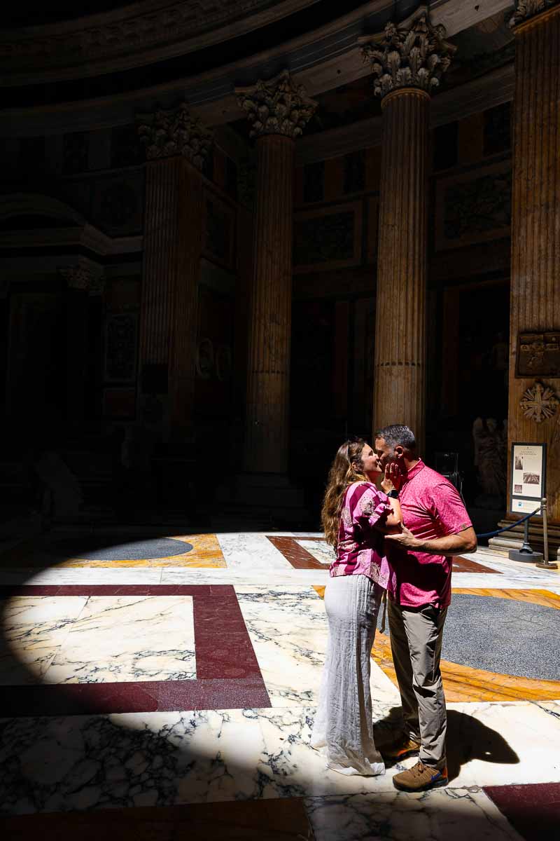 Couple sharing their first kiss after getting engaged inside the ancient Roman temple during a romantic portrait photography session