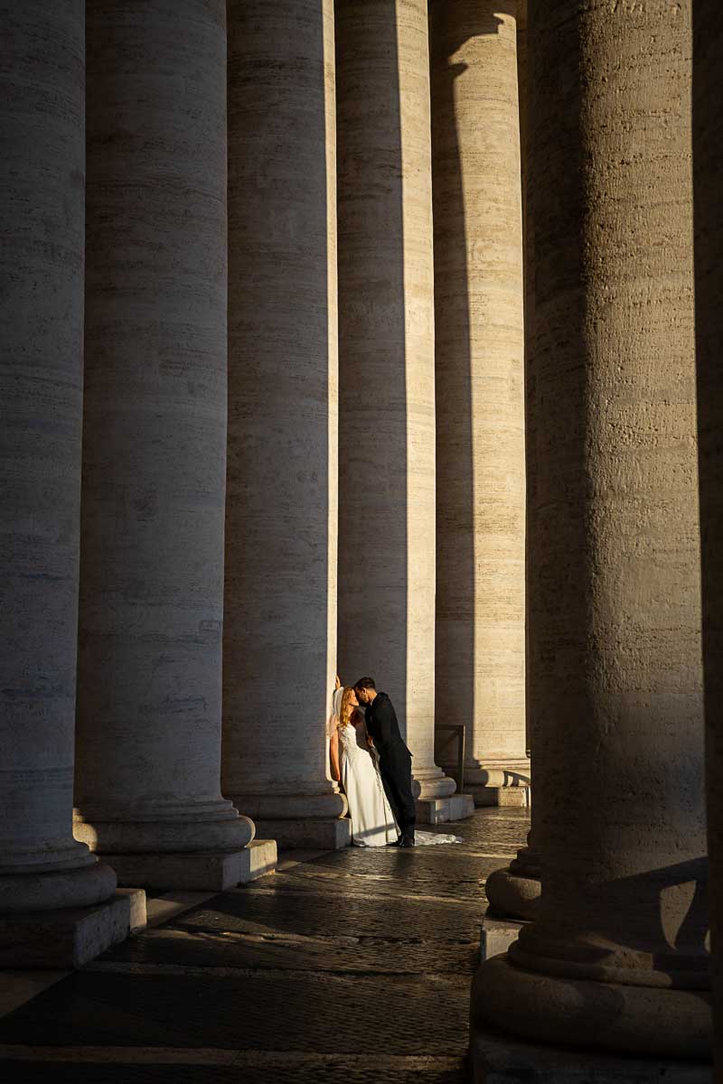 Image of the newlyweds posing next to the large columns un the colonnade
