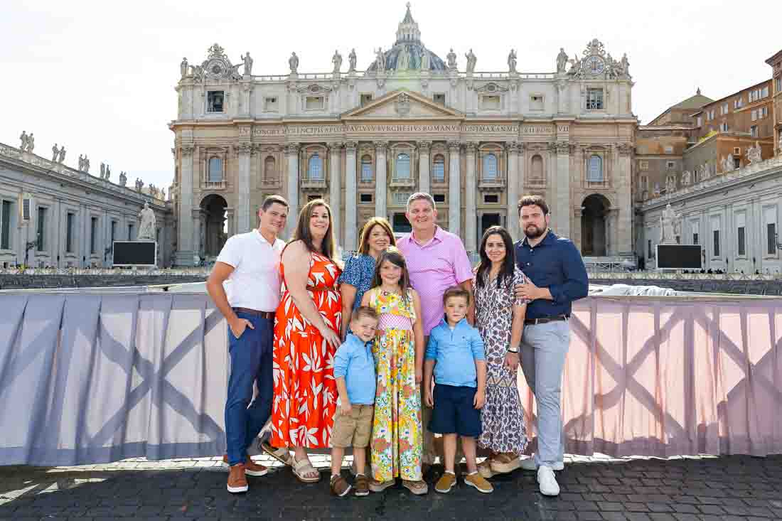 Extended family group photography standing together in front of the basilica façade overlooking the square during an outdoor portrait photo shoot in soft natural light with architectural depth in the background