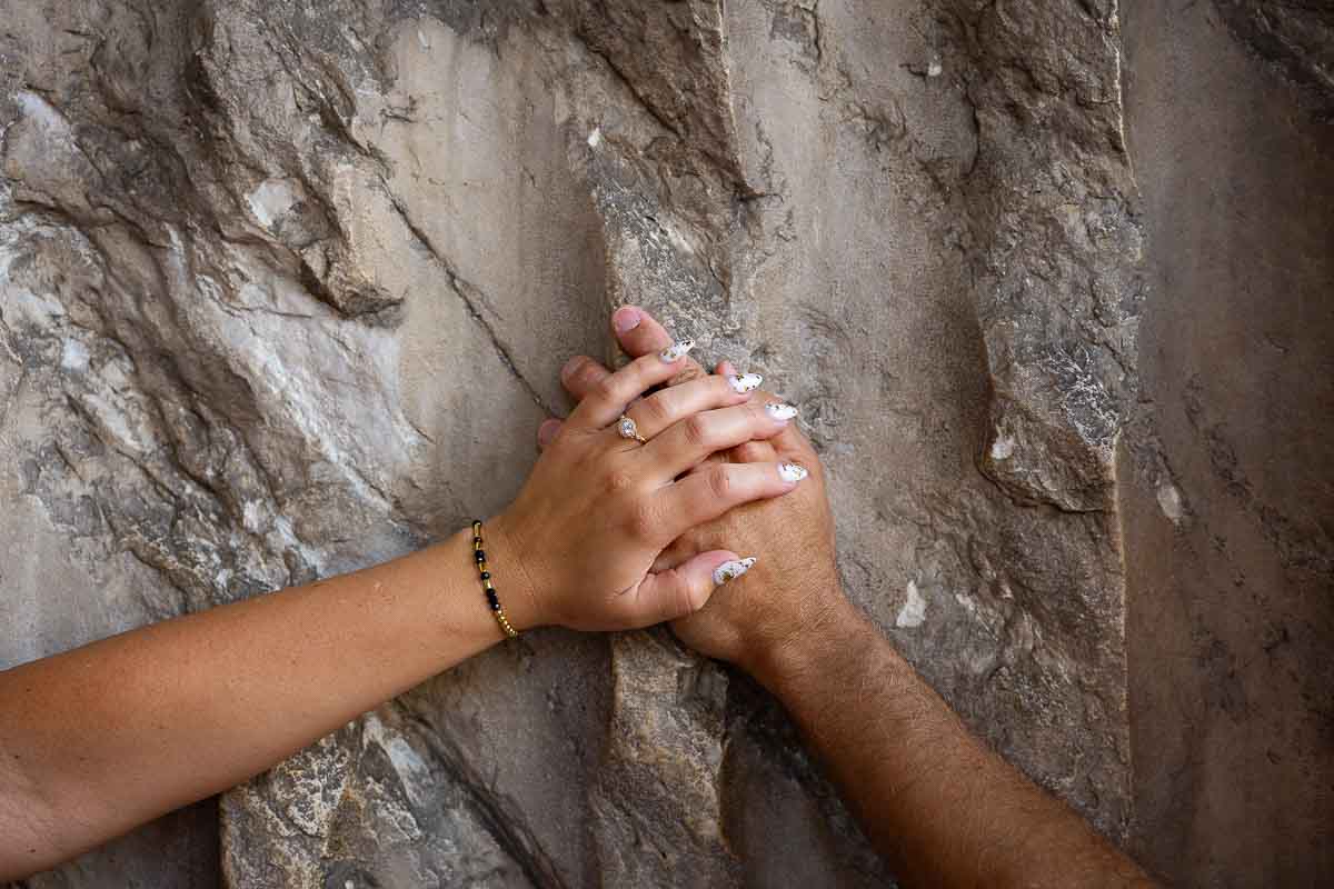 Close-up still life photograph of an engagement ring resting on a hand with ancient marble textures creating an elegant background composition