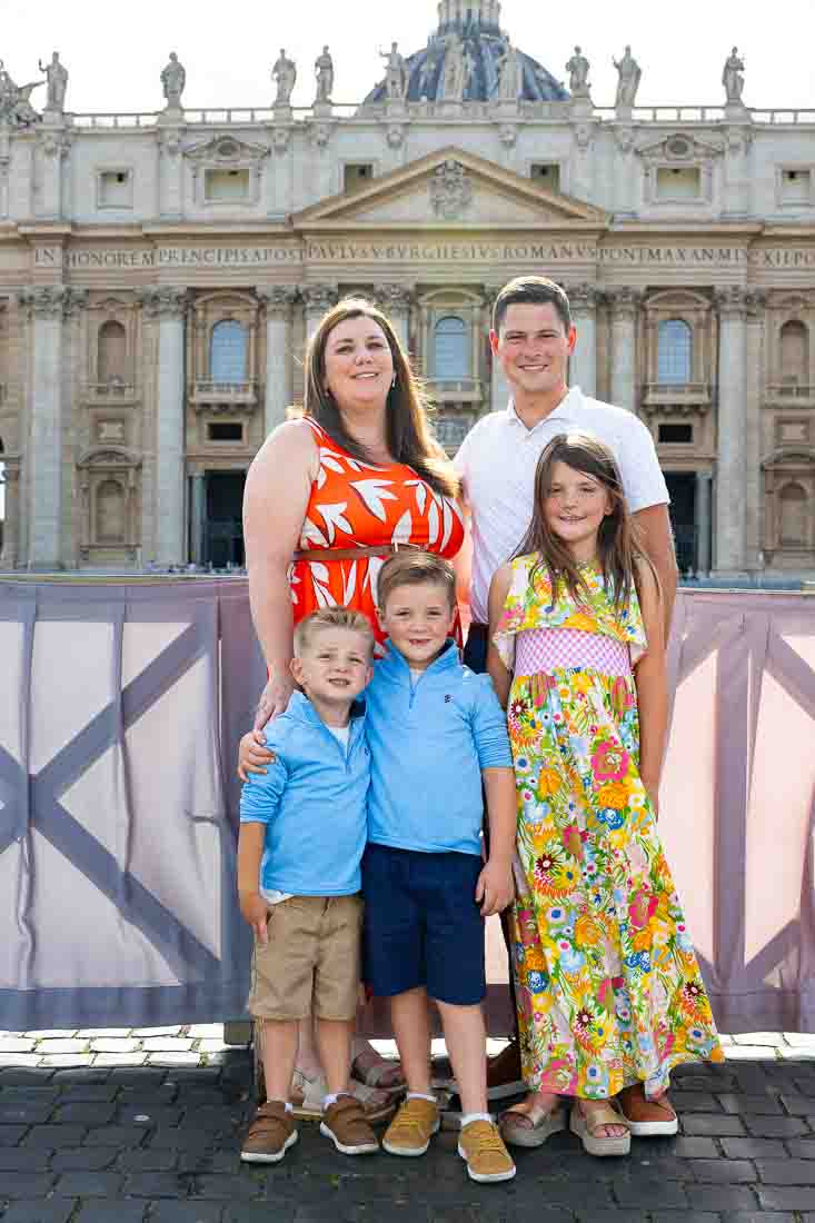 Group of relatives posed in front of basilica façade during an outdoor portrait photoshoot with architectural surroundings backdrop view