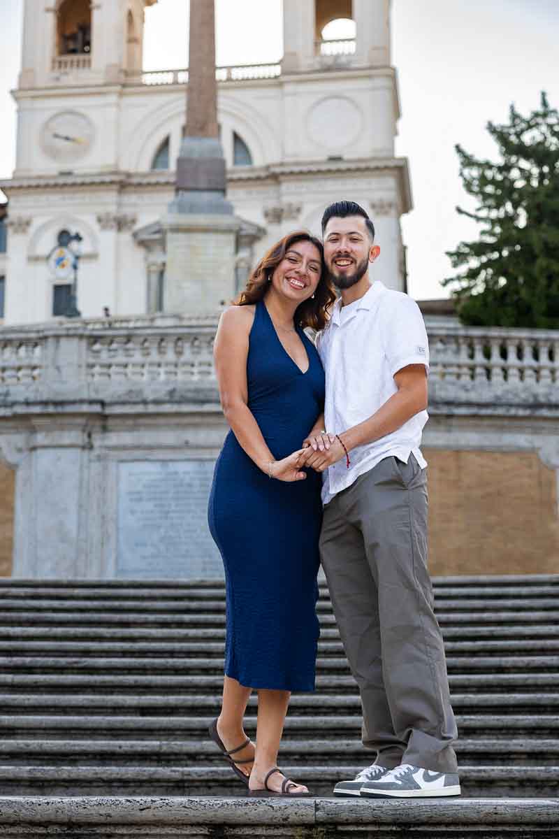 Newly engaged couple standing at the top of the Spanish Steps, captured in a romantic portrait with the historic staircase creating strong lines and depth in the composition.