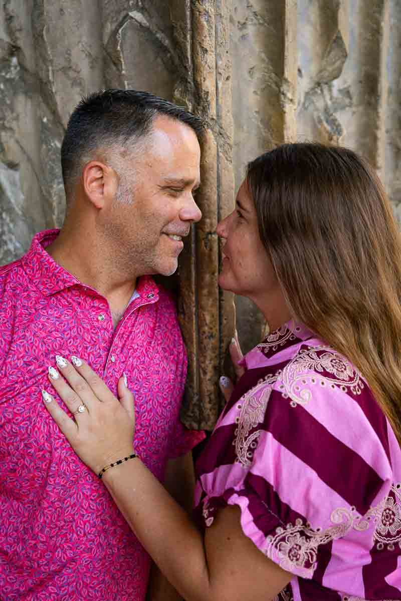 Engaged couple portrait showing the ring while standing in front of large ancient marble slabs with a historic stone backdrop