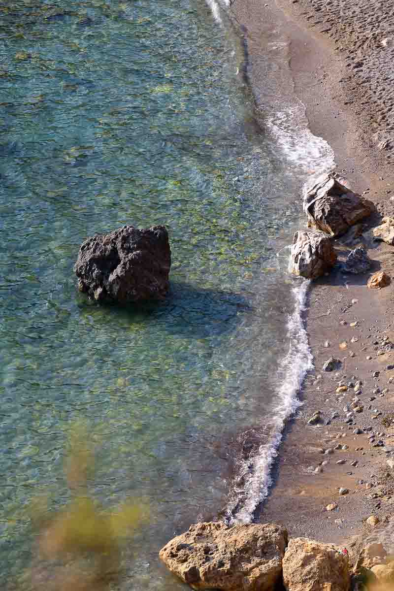 Aerial-style landscape photograph overlooking Cala del Gesso in Monte Argentario, capturing the crystal-clear turquoise water, rocky coastline, and one of Tuscany's most scenic seaside locations.