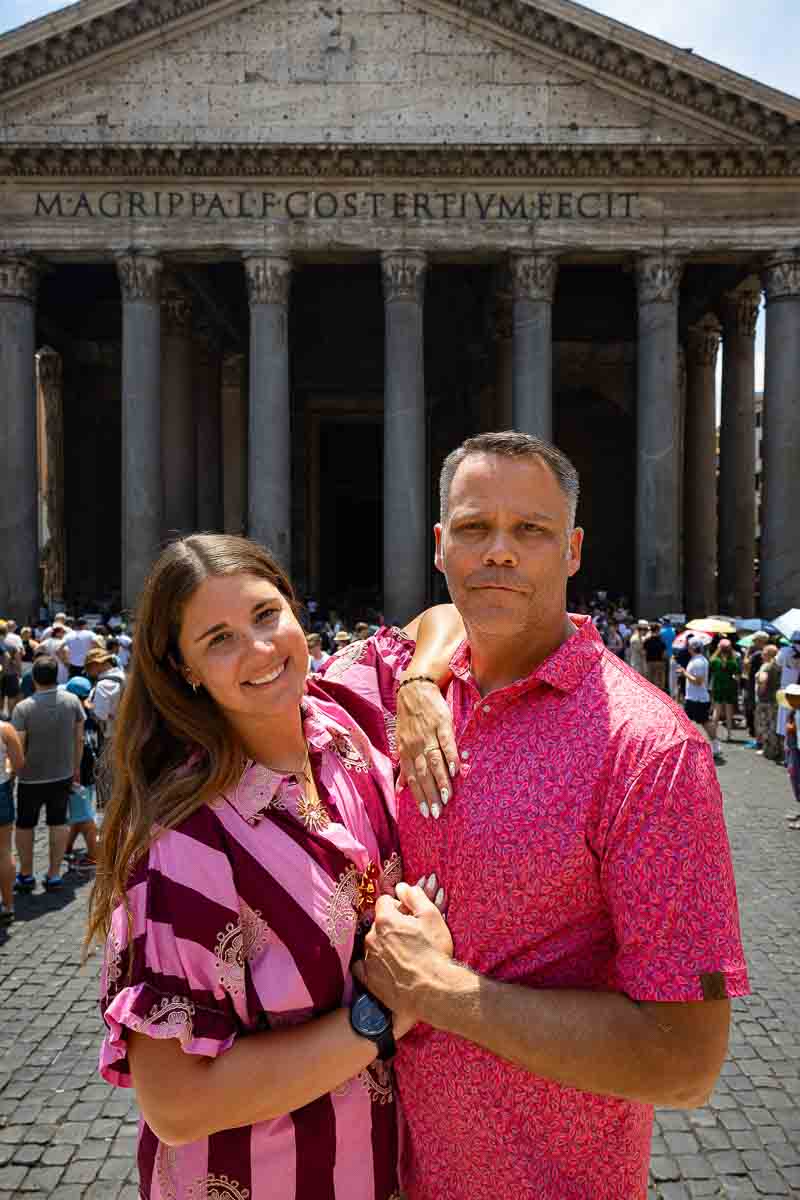 Happy couple standing together beside the grand entrance façade of the Roman Pantheon during an engagement portrait photo shoot