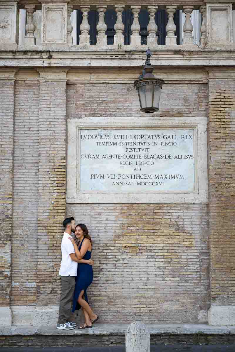 Couple standing beneath the ancient marble sign during a romantic photoshoot, creating a natural portrait with historic stone textures and refined composition.