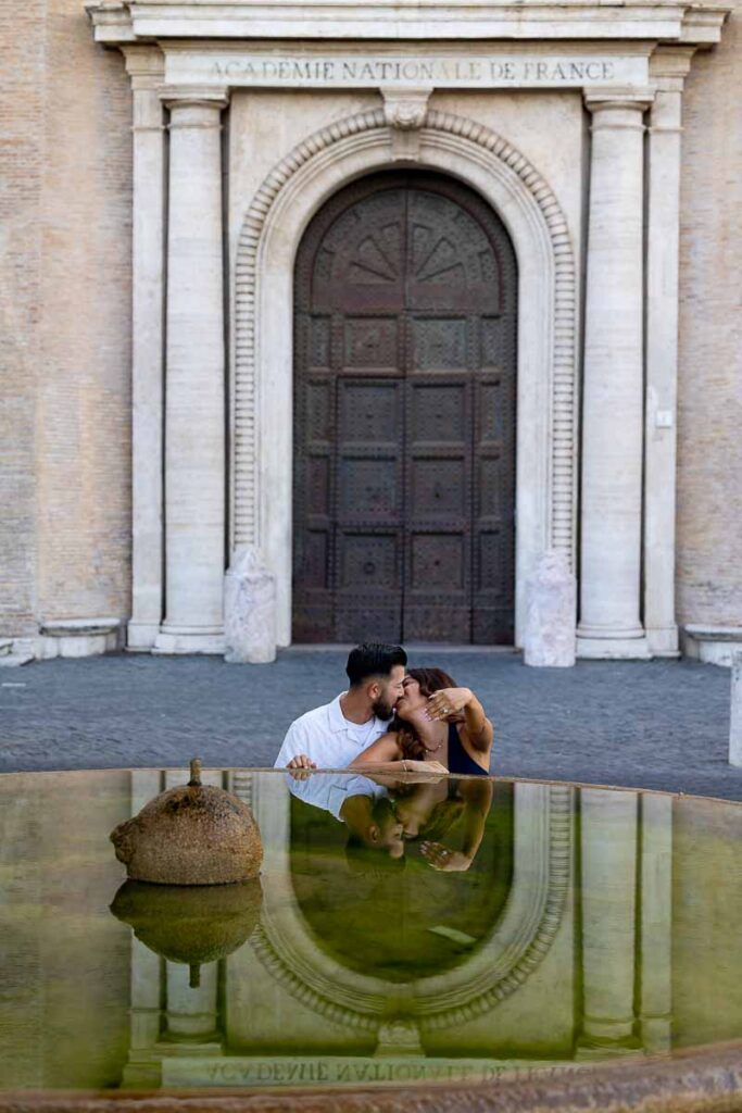 Couple portrait reflecting beside a tranquil water fountain, captured through a serene visual composition with natural tones and a refined engagement photoshoot style.